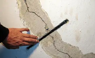 A wall with a large crack is being inspected by a professional in Charleston, SC
